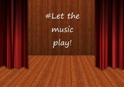 Empty theatre stage with "Let the music play" written on the back wall